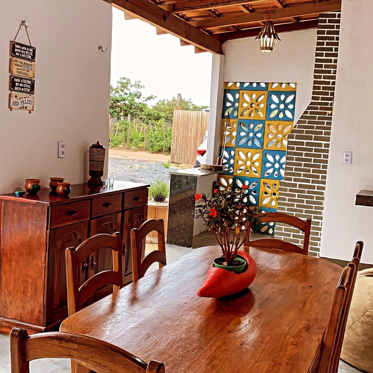 Área de jantar interna com mesa de madeira maciça e azulejos decorativos