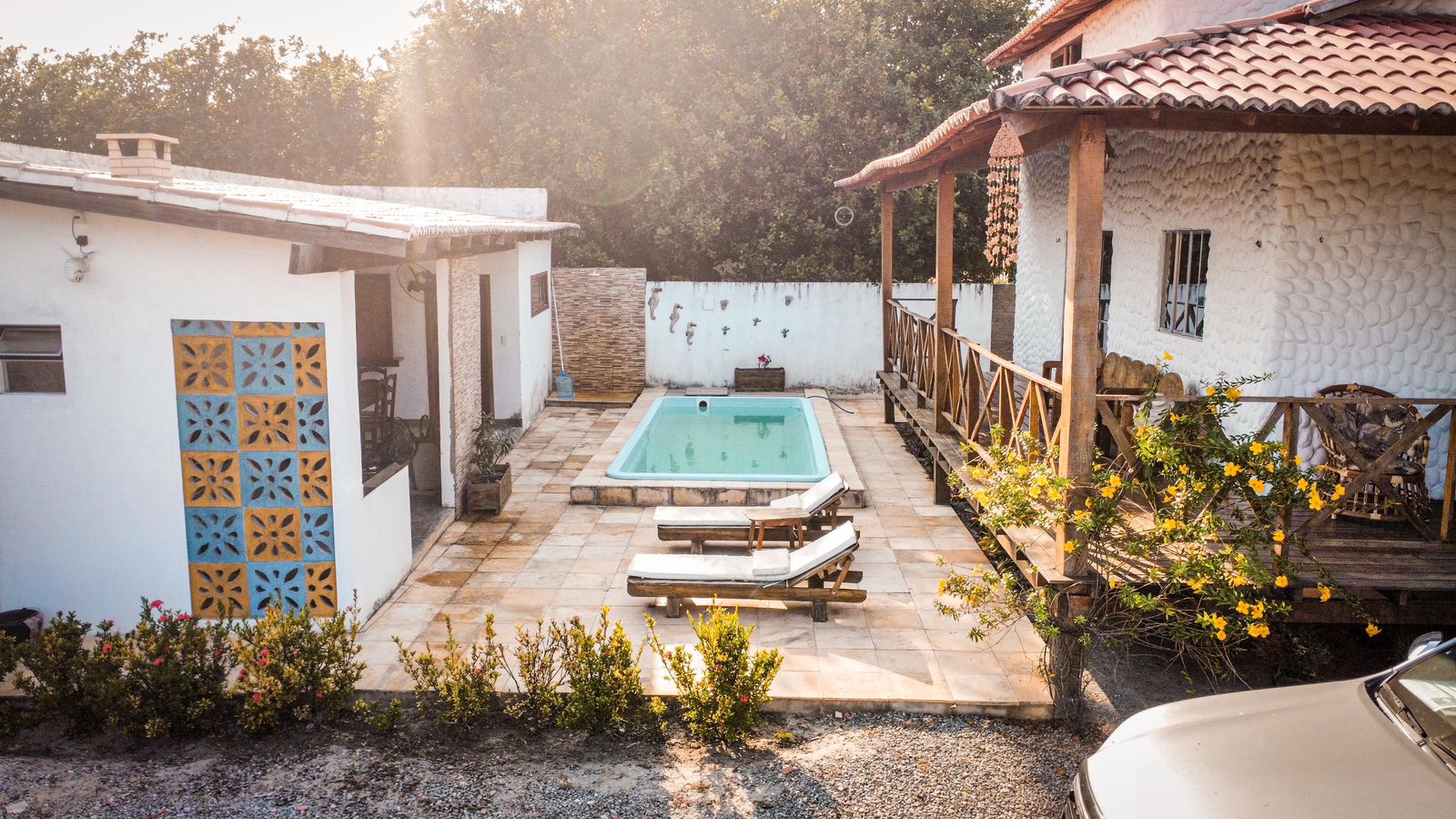 Área da piscina com espreguiçadeiras e paisagismo tropical