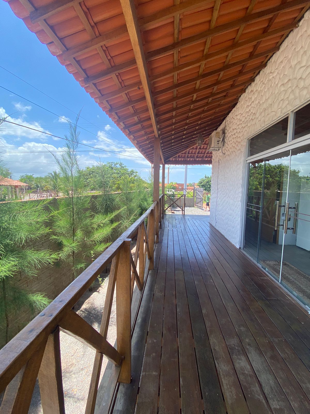 Corredor da varanda com piso de madeira e vista para vegetação